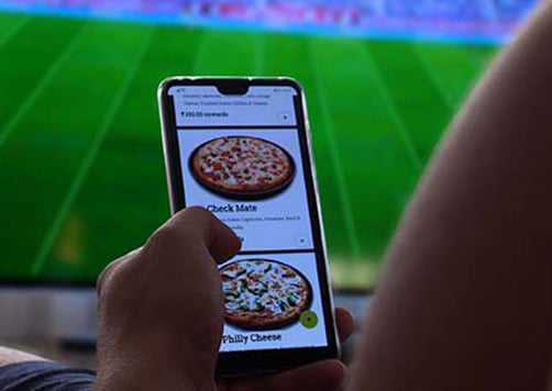 ordering a pizza on cellphone while at a sporting event