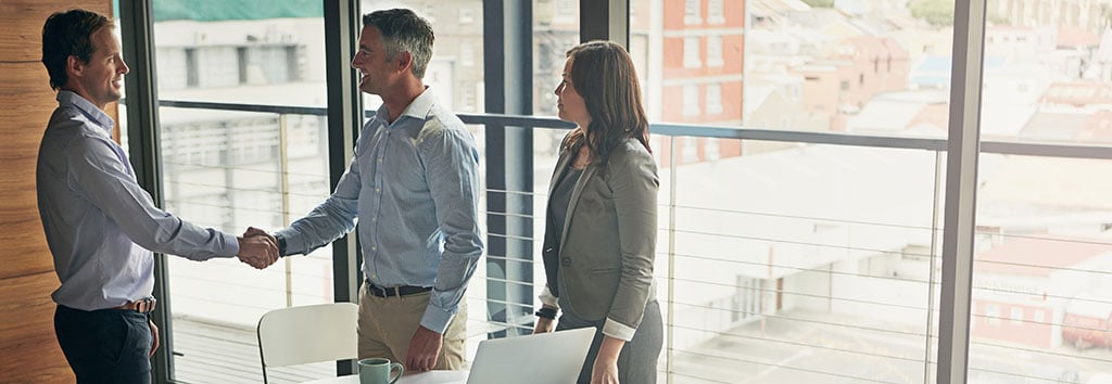 A client and insurance provider shake hands at the beginning of a business meeting