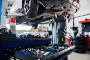 Employee at a mechanical repair shop working underneath a customer car.