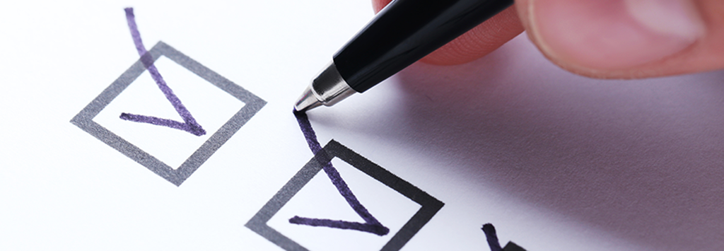 person drawing a checkmark in a checkbox using a pen