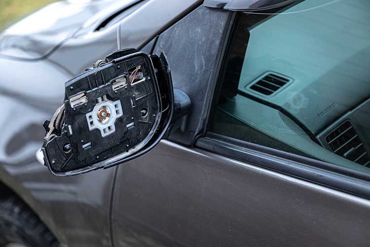 Image of a damaged side view mirror due to backing a customer's vehicle into a building.