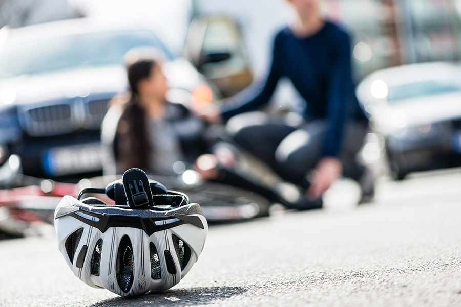 Image of a couple sitting on the road with a helmet on the ground in front of them.