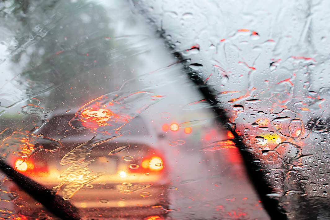 View through a car's front windshield driving through a rainstorm.