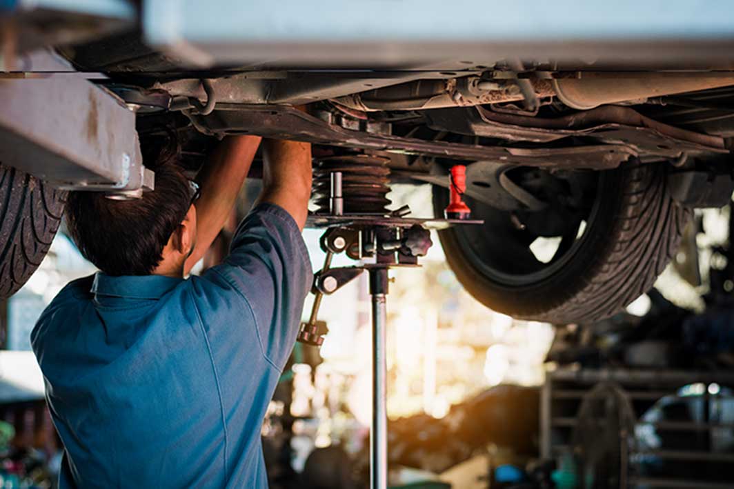 Auto repair shop employee working underneath a customer's vehicle.